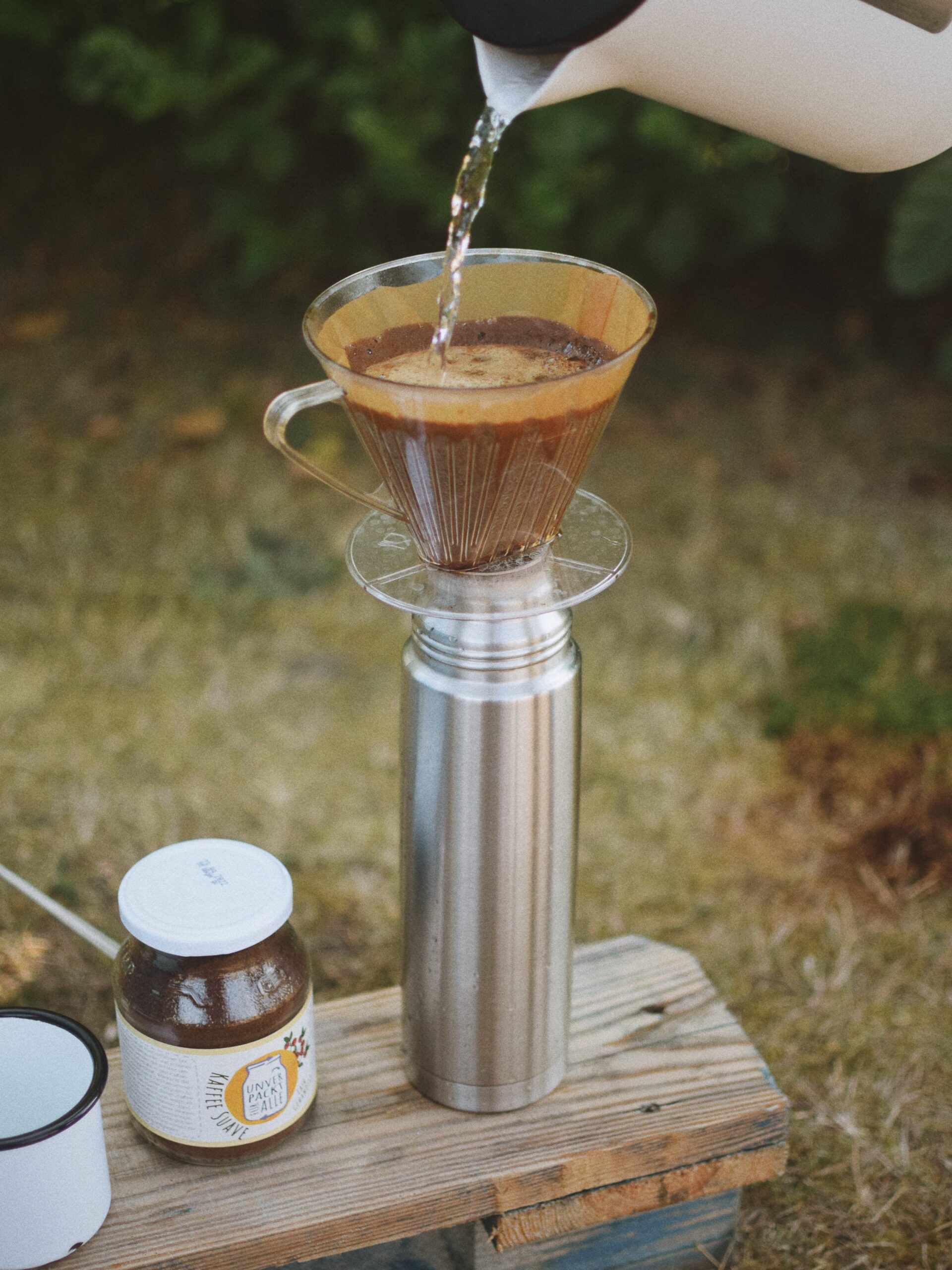 filterkaffee läuft in thermoskanne, daneben kaffee im mehrwegglas